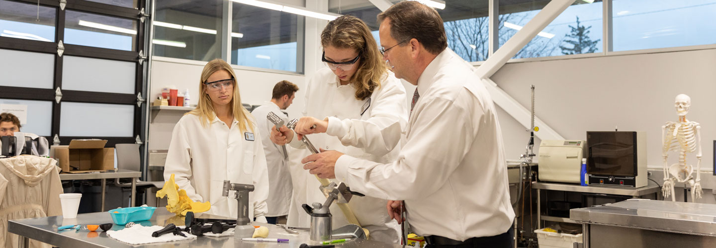 Professor Phlipot assisting a student in installing a pin in a fake bone